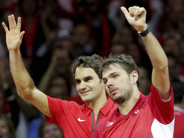 Federer, left, and compatriot Stanislas Wawrinka, right wave after defeating French pair Julien Benneteau and Richard Gasquet