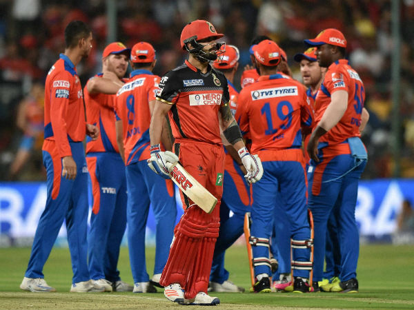 Royal Challengers Bangalore's Virat Kohli returns the pavilion as Gujarat Lions players celebrate.