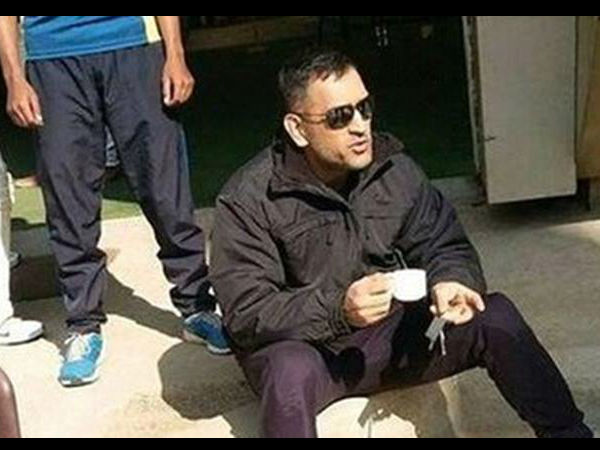 Dhoni sipping tea while sitting on the ground
