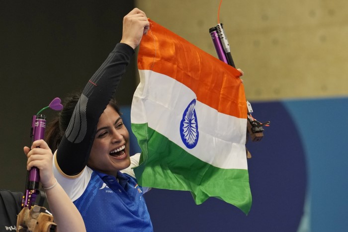India's Manu Bhaker celebrates with the Indian flag after winning the bronze medal in the 10m air pistol women's final round at the 2024 Summer Olympics, Sunday,