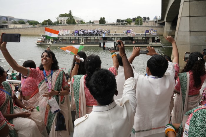 Indian athletes take selfies and photograph standing in a boat in Paris, France, before the start of the opening ceremony of the 2024 Summer Olympics, Friday, July 26, 2024.