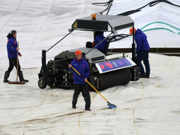 మైదానాన్ని కవర్లతో కప్పి ఉంచిన సిబ్బంది మైదానాన్ని కవర్లతో కప్పి ఉంచిన సిబ్బంది